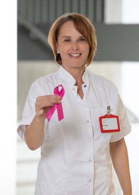 Foto: Foto Muik DGKP Katja Maria Knopf, Dipl. Gesundheits- und Krankenpflegerin, mit rosa Schleife in der rechten Hand