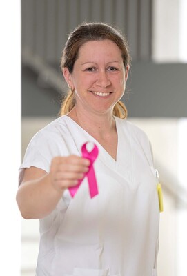 Foto: Foto Muik DGKP Sandra Laky, Dipl. Gesundheits- und Krankenpflegerin, mit rosa Schleife in der rechten Hand