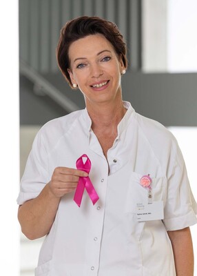 Foto: Foto Muik DGKP Silvia Jaindl, BSc Dipl. Gesundheits- und Krankenpflegerin, mit rosa Schleife in der rechten Hand