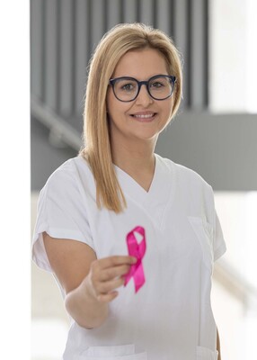 Foto: Foto Muik DGKP Katharina Steif, Dipl. Gesundheits- und Krankenpflegerin, mit rosa Schleife in der rechten Hand