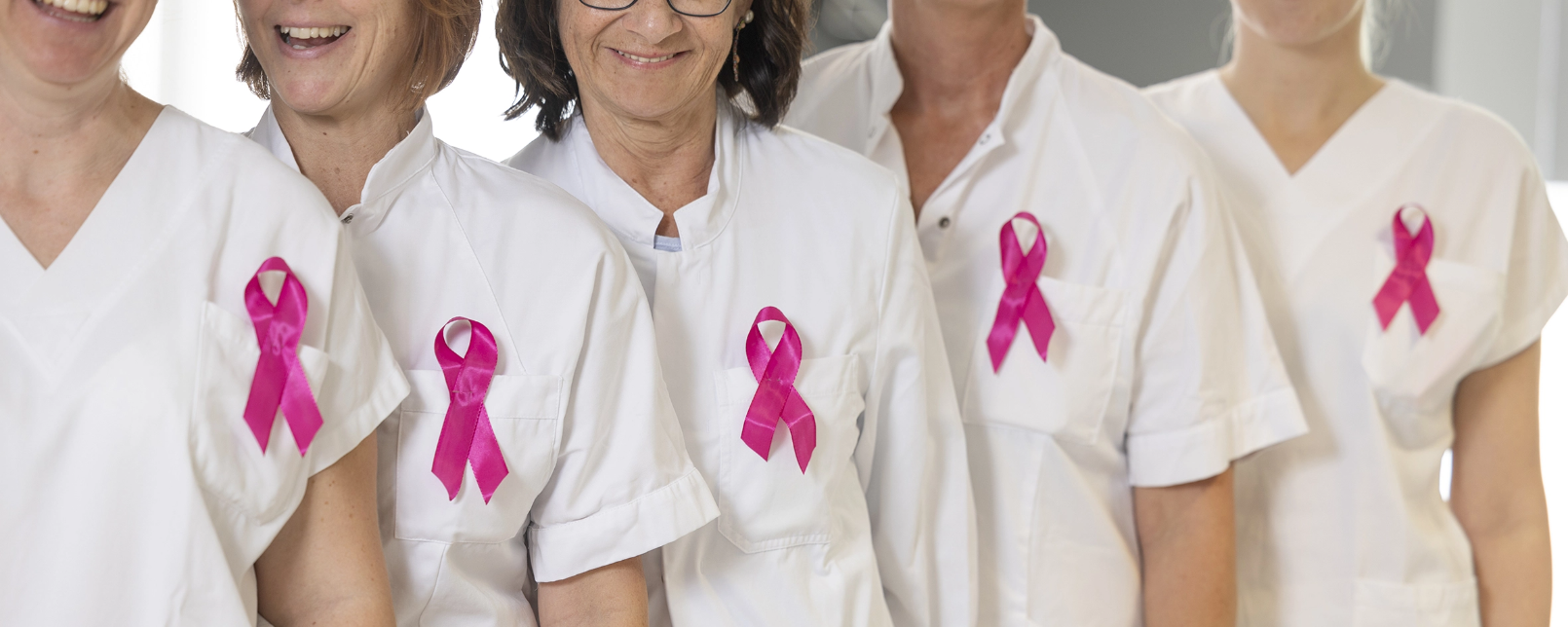 Frauen in weißer Dienstkleidung mit rosa Brustkrebs-Schleife 